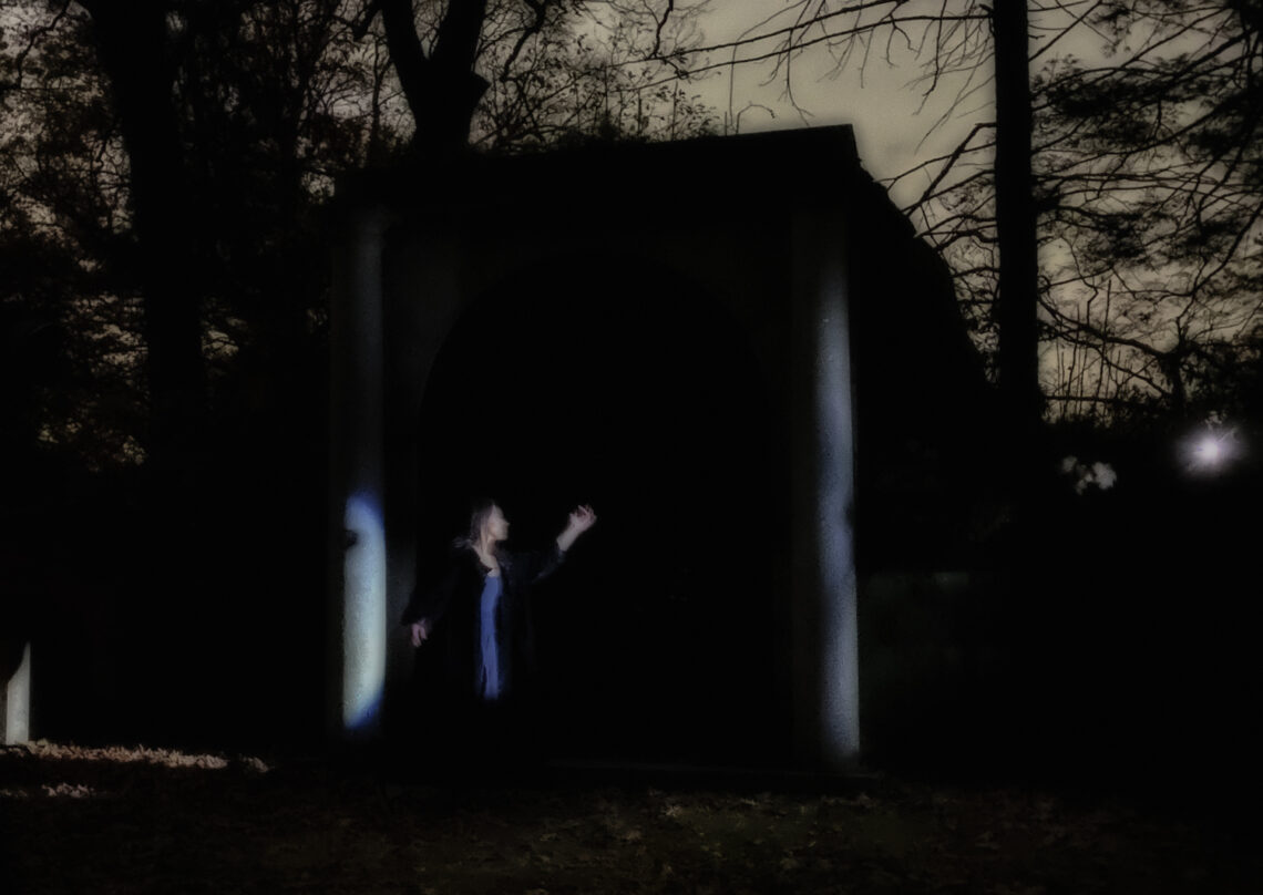 A woman in black poses on a dark night in Sleepy Hollow.