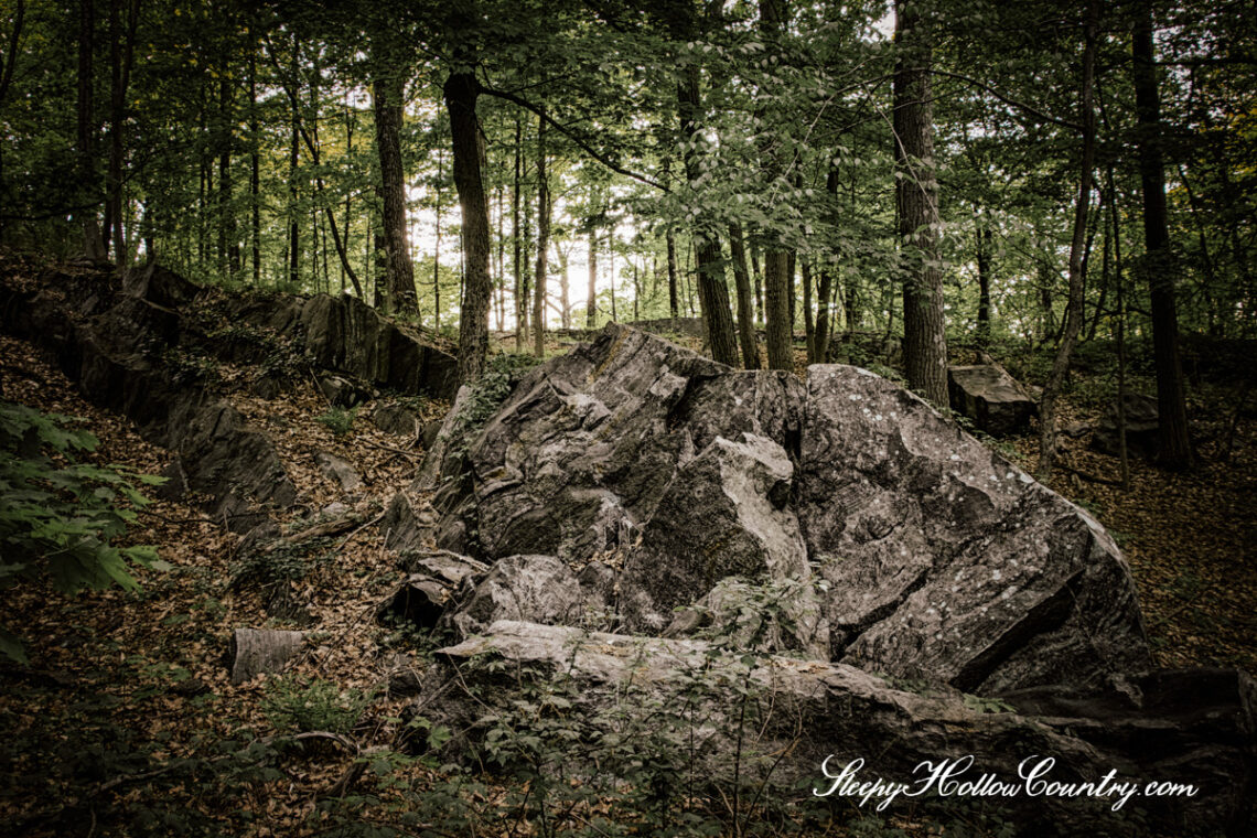 A jagged rock formation on Buttermilk Hill is framed against gloomy woodlands.