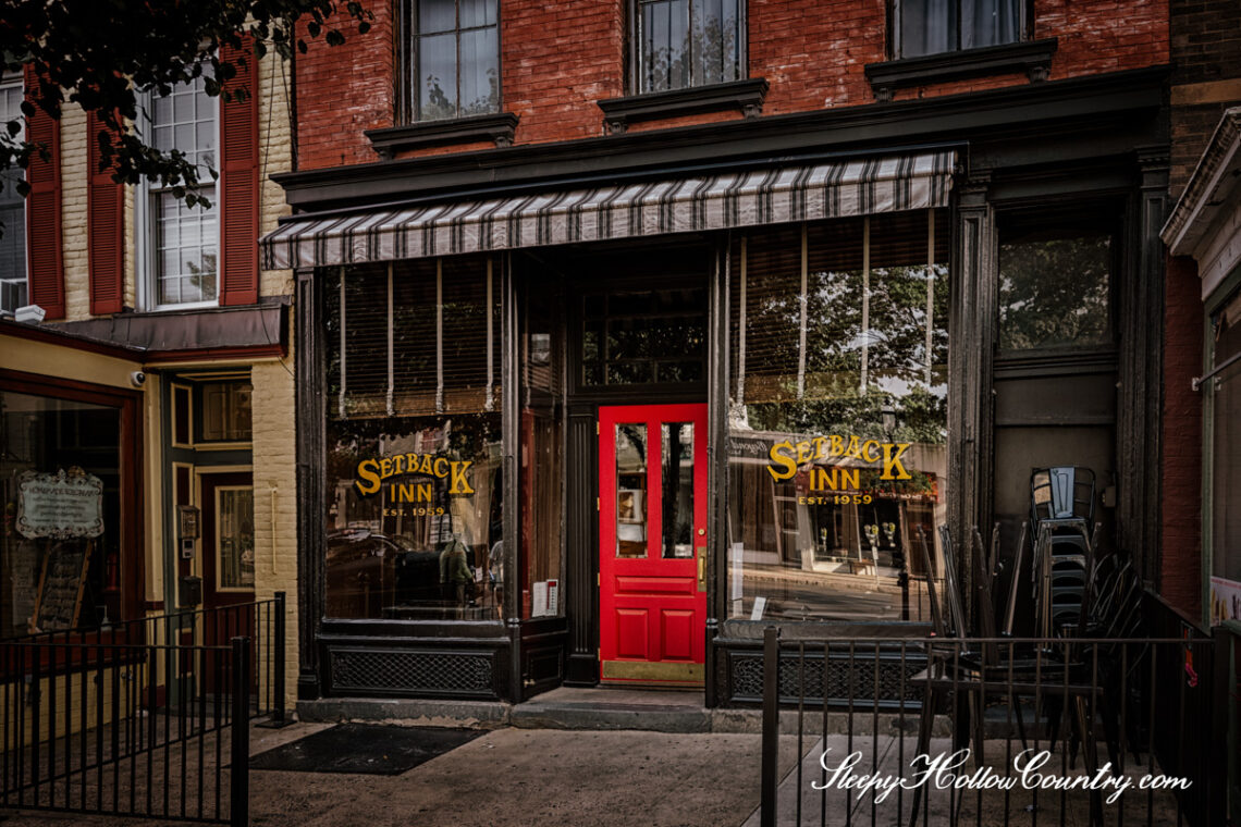 One of three haunted taverns of Sleepy Hollow Country, Set Back Inn in Tarrytown, NY has a red door between two plate glass windows.